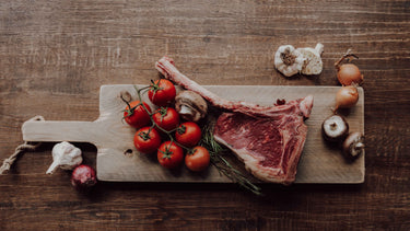 Ein schönes Brett, belegt mit Tomaten, Fleisch und Champignons