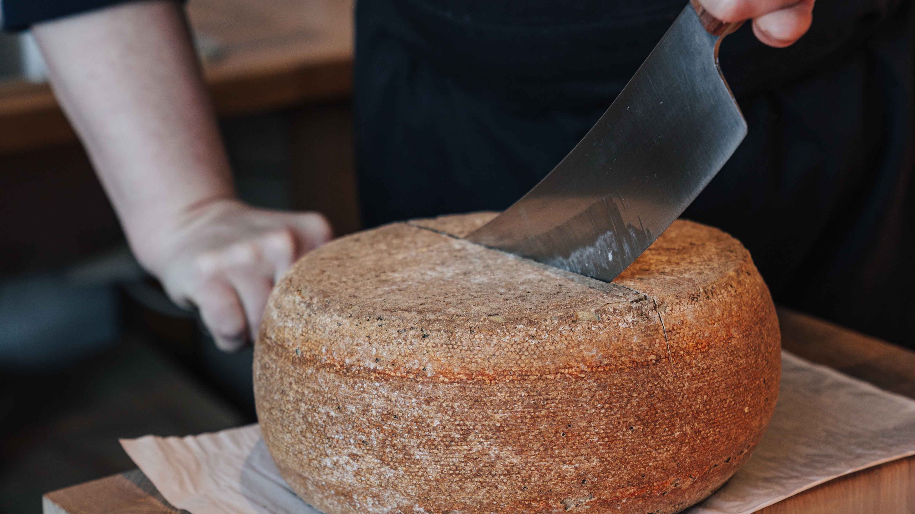 Der Name Ihrer Sammlung Ein Käselaib wird mit einem Wiegemesser durchgeschnitten