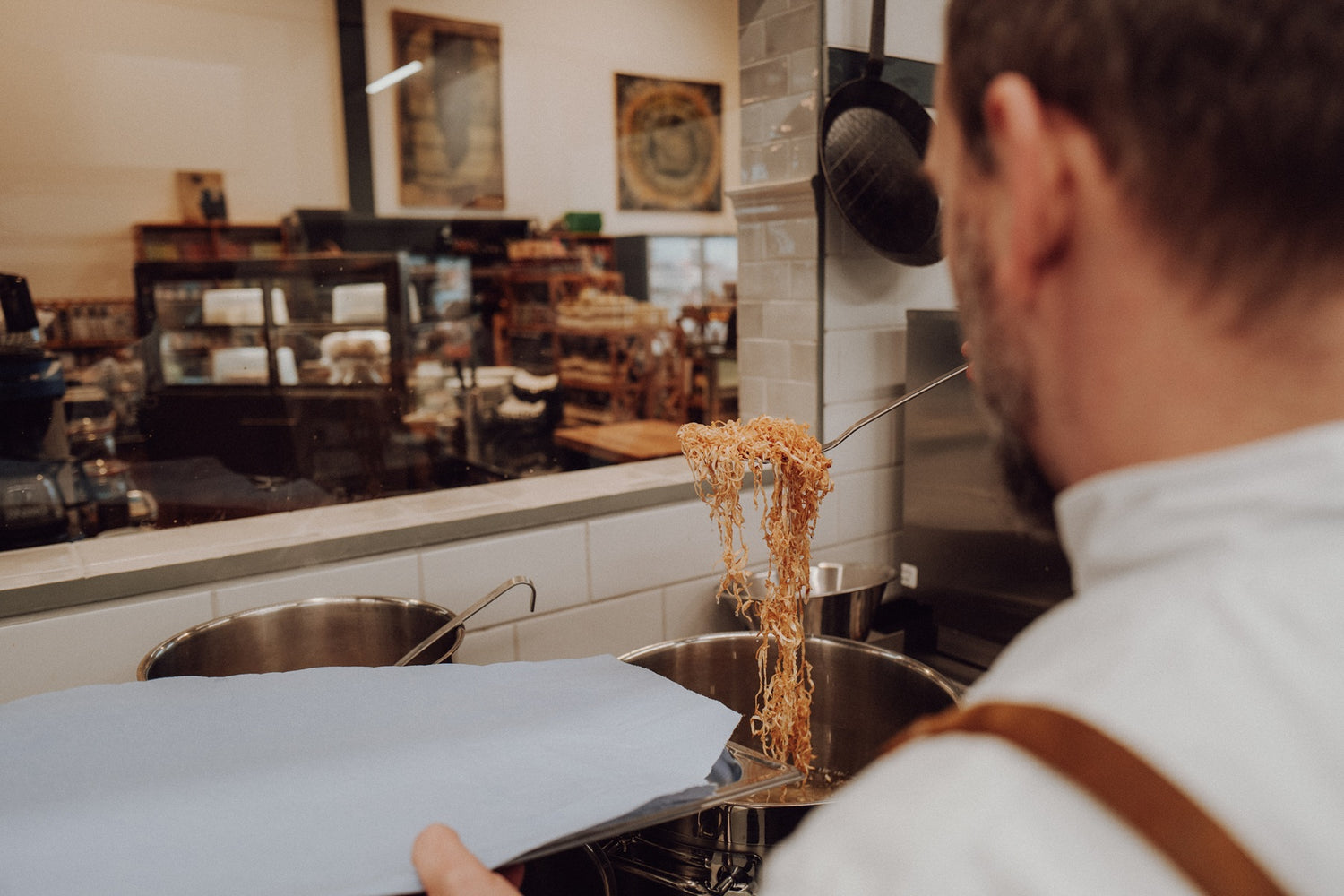 Ein Koch steht in der Küche und schöpft Pasta