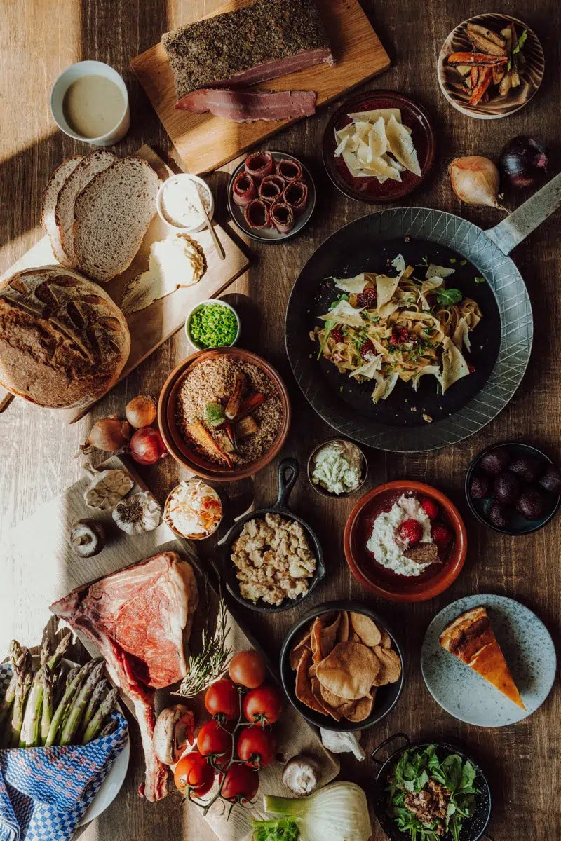 Hier sieht man einen sehr lecker gedeckten Tisch mit Brot, Kuchen, Fleisch und Pasta