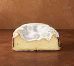 Ein halber Vacherin Käse liegt  vor einem braunen Hintergrund