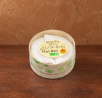 Ein Vacherin Käse liegt in einer Verpackung vor einem braunen Hintergrund
