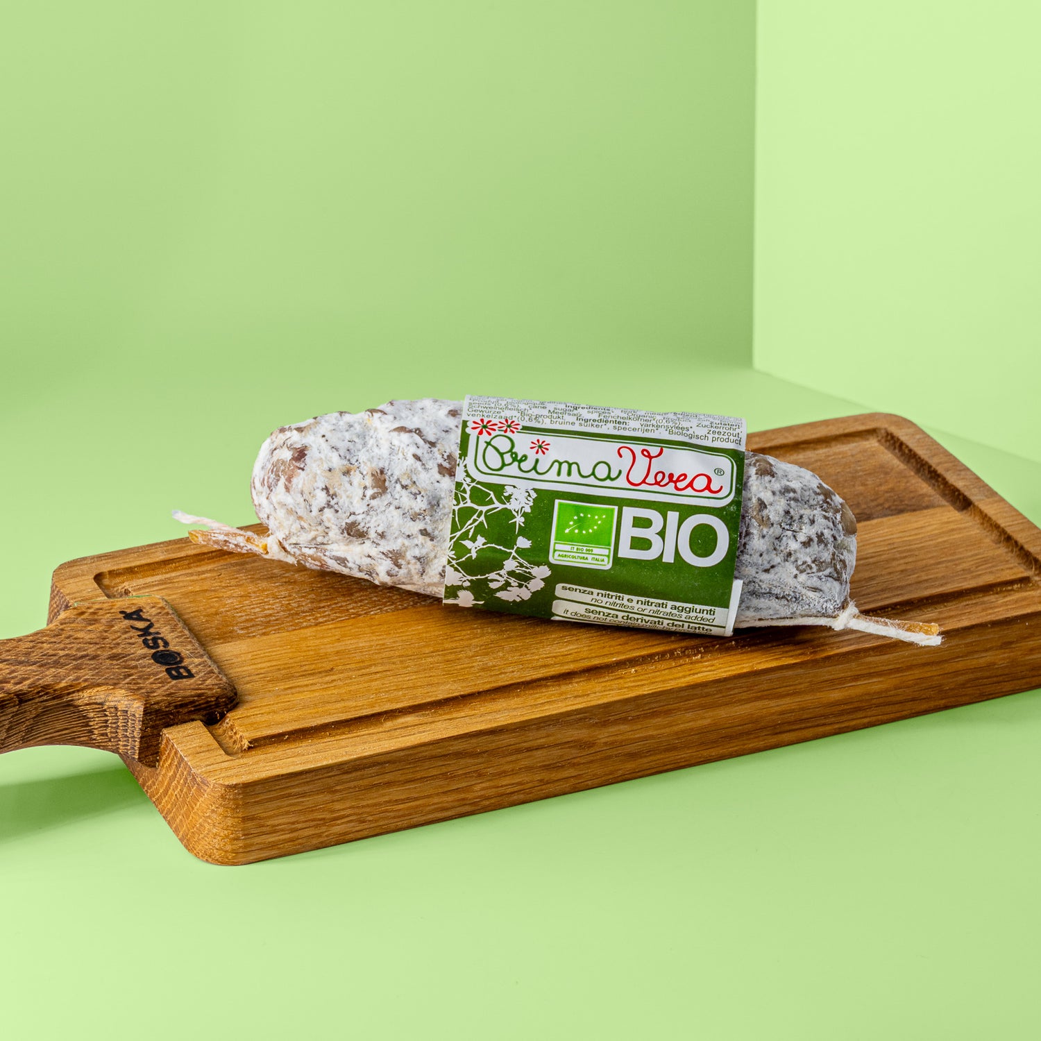 Fenchel Salami mit grün weißer Banderole auf Holzbrett.