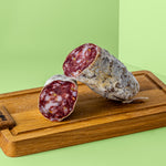Zwei halbe Stücke Fenchel Salami auf Holzbrett.
