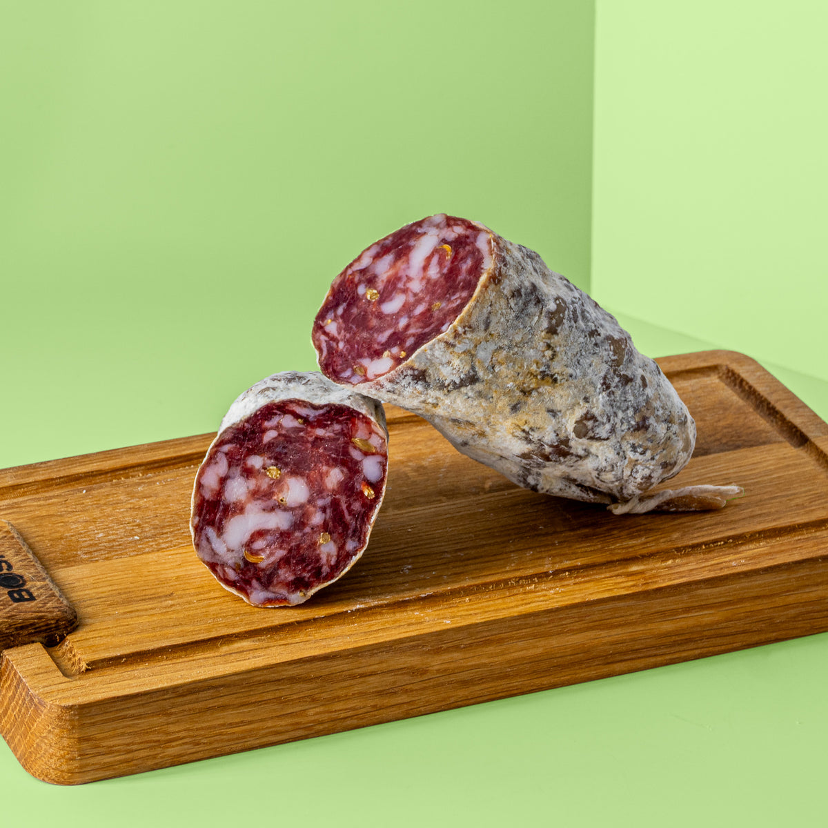 Zwei halbe Stücke Fenchel Salami auf Holzbrett.