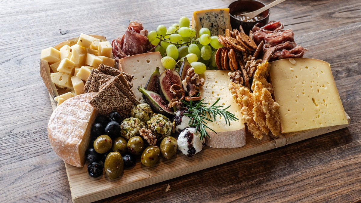 Ein vielfältiges Käsebrett mit verschiedenen Sorten Käse, Obst und Salami