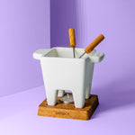 Käsefondue Topf, zwei Bestecke mit Holzgriffen, einem Holzuntersetzer drunter für Teelicht.