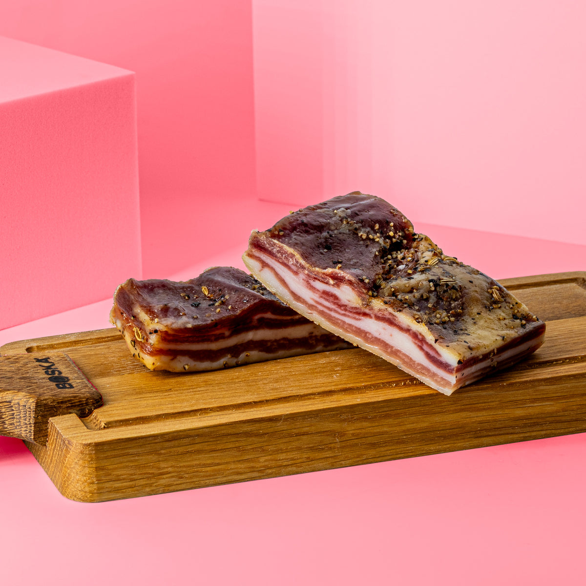 Zwei Stücke Mini Pancetta auf Holzbrett