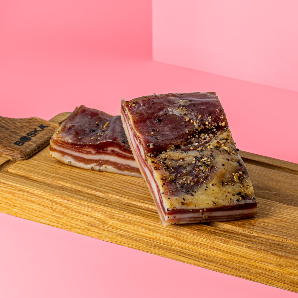 Zwei Stücke Mini-Pancetta auf Holzbrett