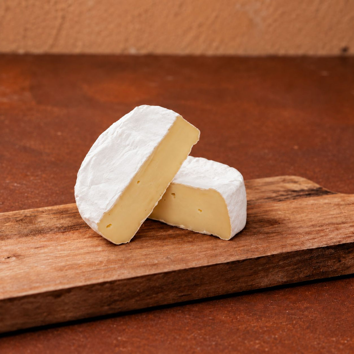 Zwei Hälften Weichkäse angeschnitten auf Holzbrett