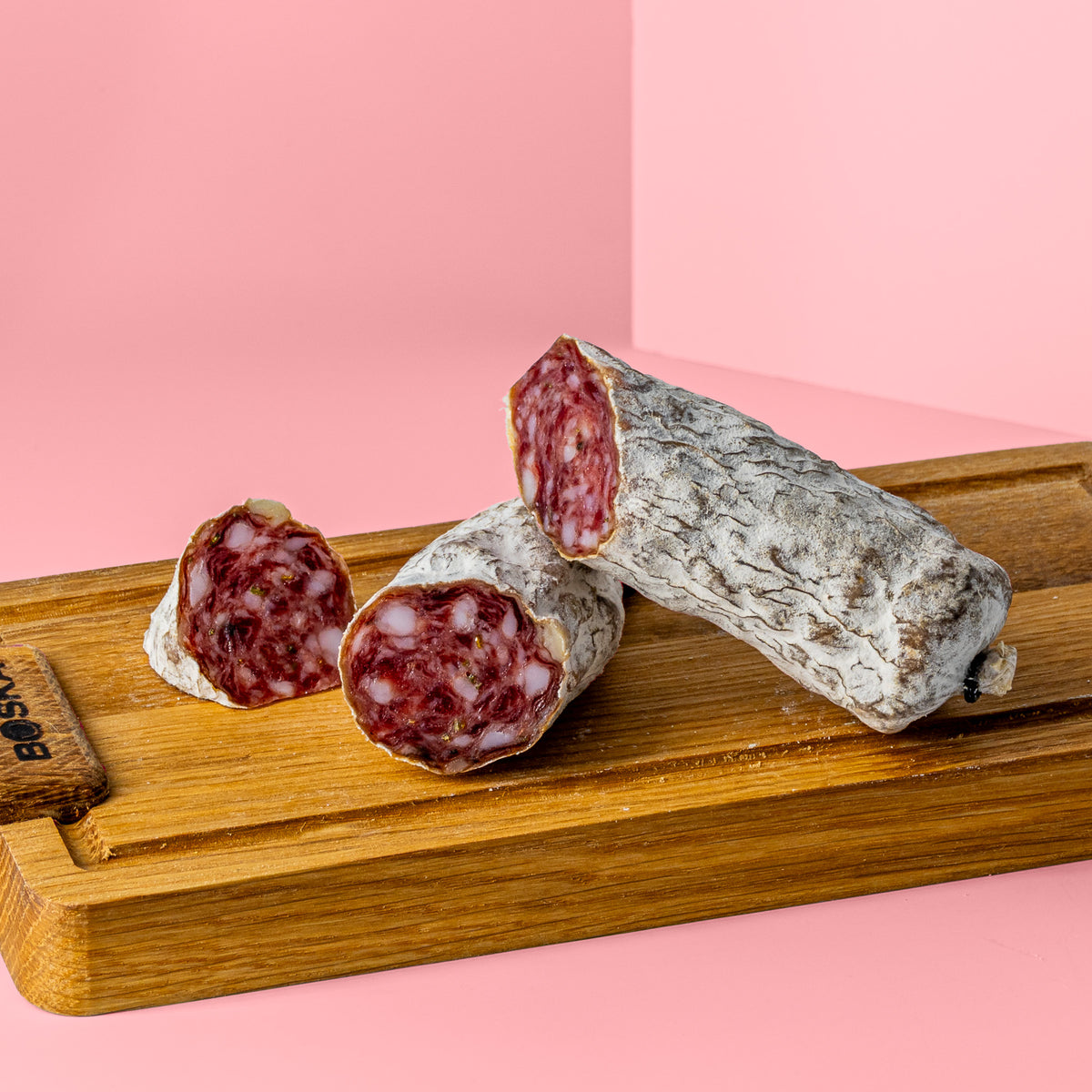 Angeschnittene Rosmarin Salami auf Holzbrett.