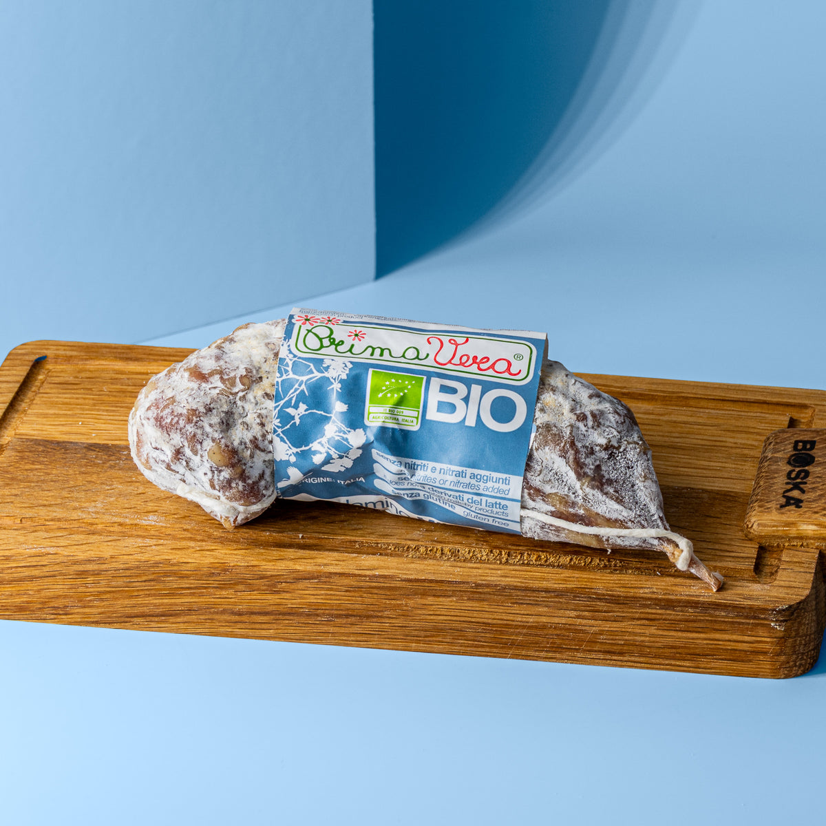 Salami Milano mit blau weißer Banderole auf Holzbrett.