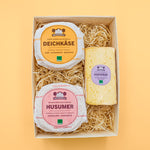 Deichkäse, Husumer und Hofkäse in Geschenkbox mit Holzwolle von oben.