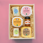 Käsesorten und Glas Tomatenrelish von oben, in Holzbox mit Holzwolle gefüllt.