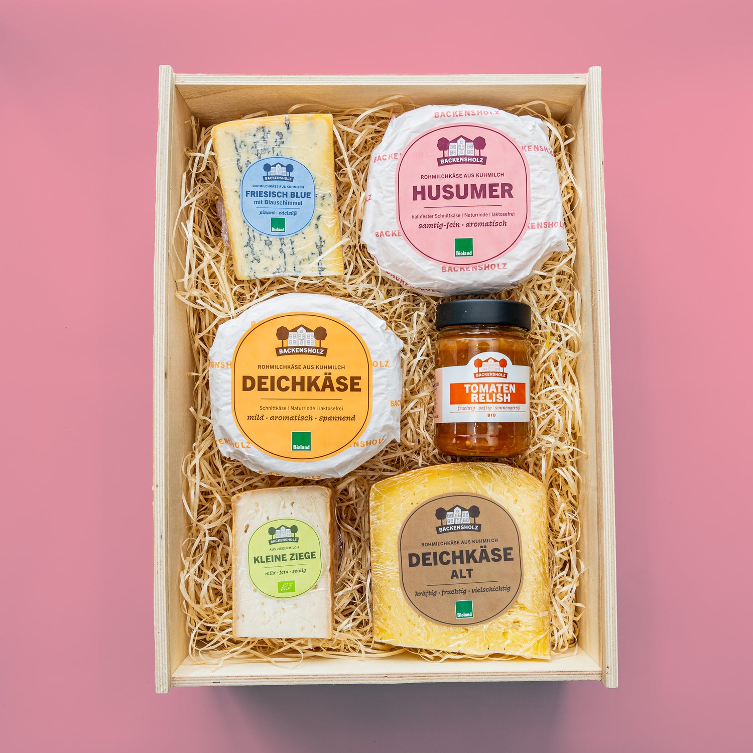Käsesorten und Glas Tomatenrelish von oben, in Holzbox mit Holzwolle gefüllt.